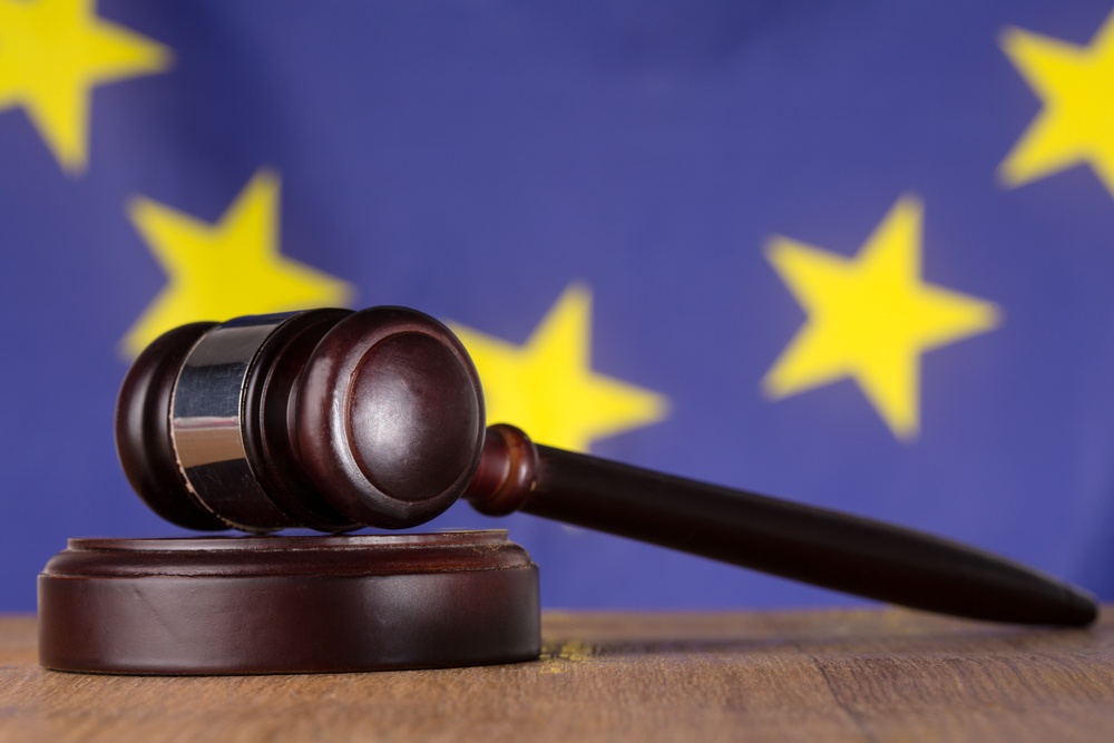 an image of European Union flag and a gavel on a wooden desk in front 