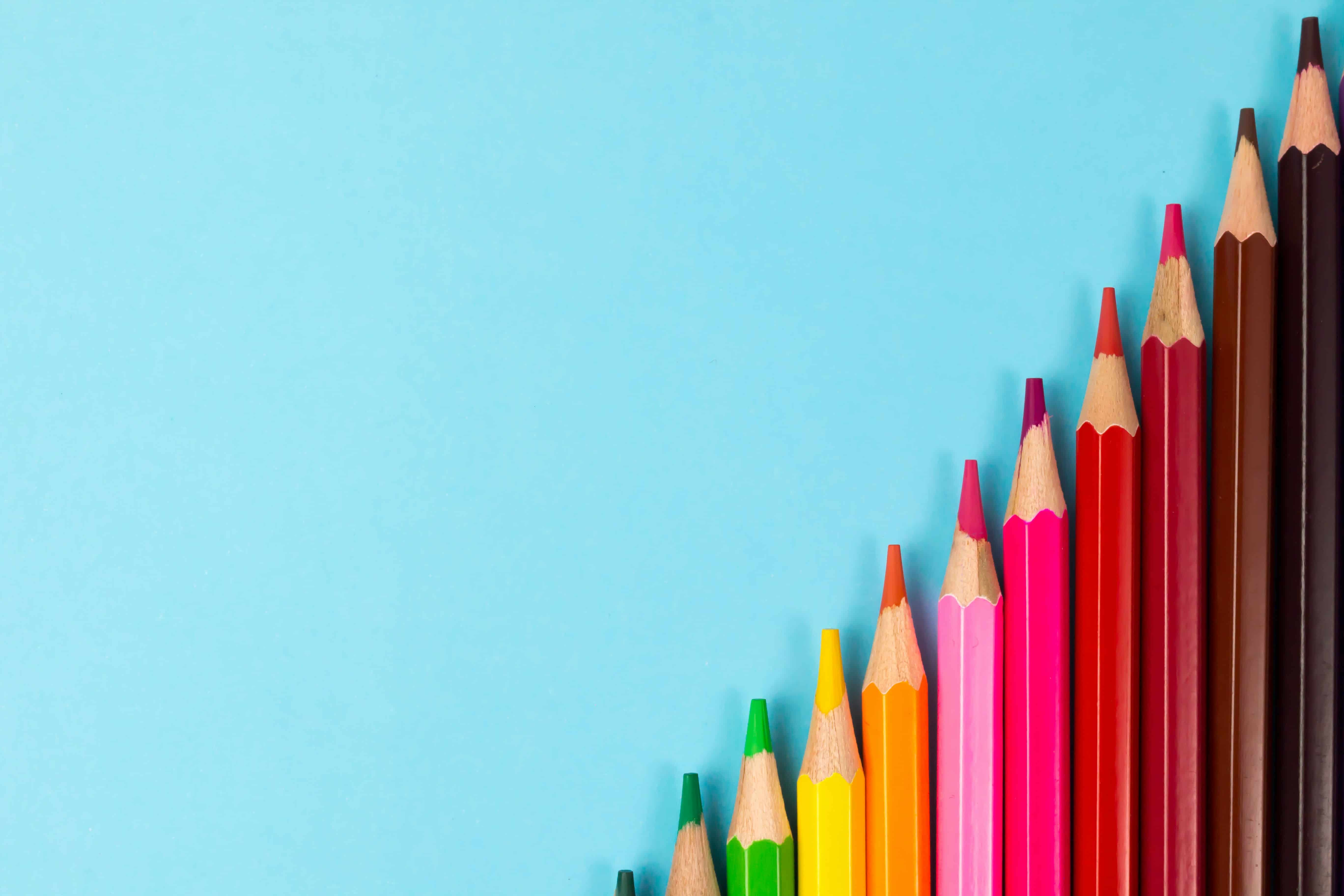 a row of colorful wooden pencils on a blue background for kids going back to school