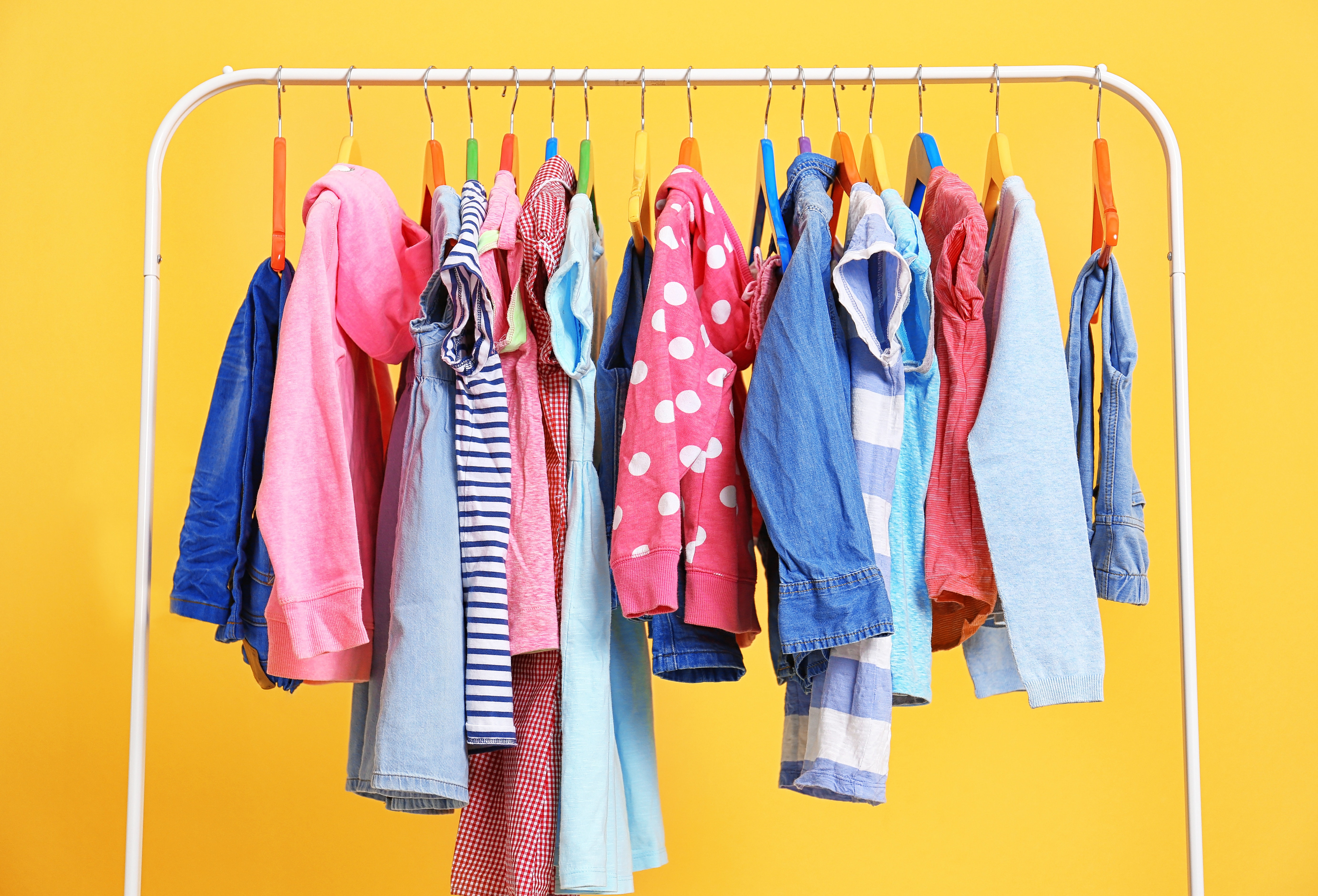 A clothing rack with colorful apparel on a yellow background 