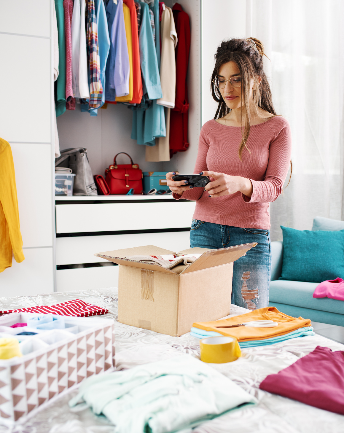 woman taking pictures of clothing items in a box to resell