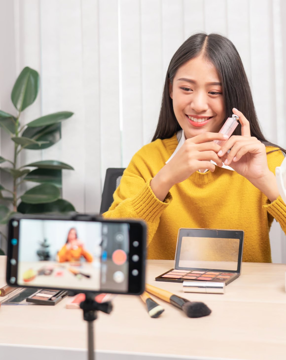  A cheerful woman holds a makeup brush, radiating joy and confidence in her beauty routine.