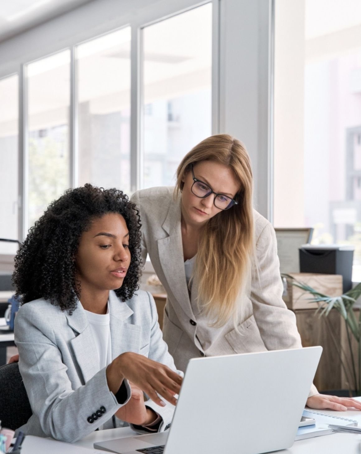 two women conversing and looking at a laptop