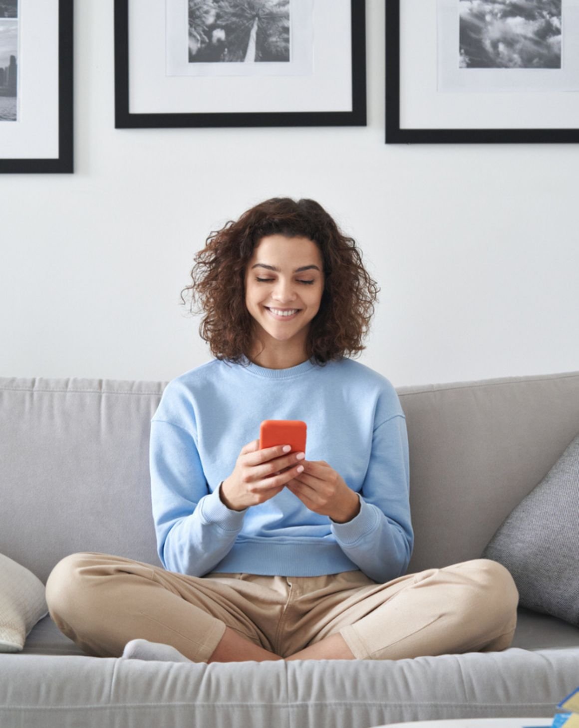 a woman sitting on a couch on her phone 