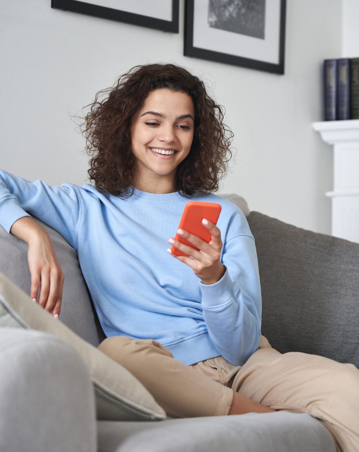 woman smiling, holding phone, sitting on couch