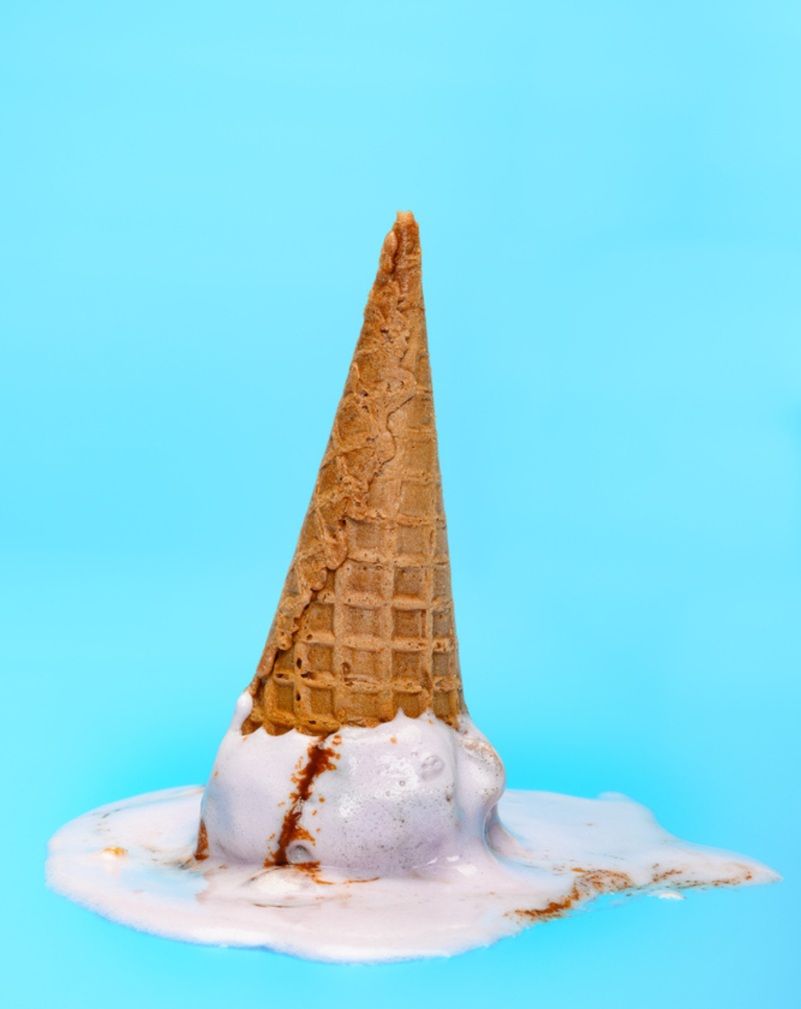 melted ice cream cone upside down against blue background