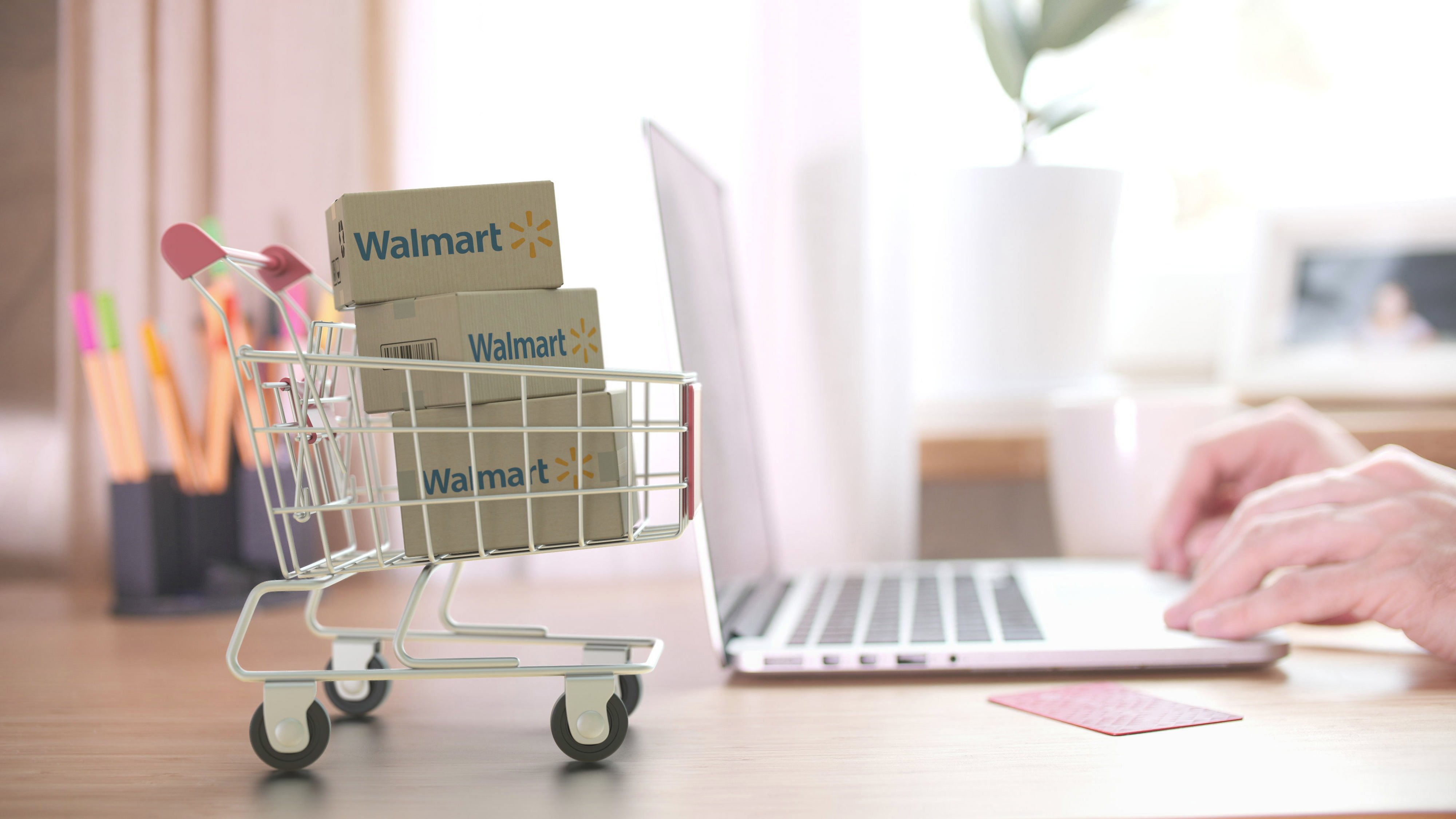 A small shopping cart with Walmart boxes and a person working on a laptop