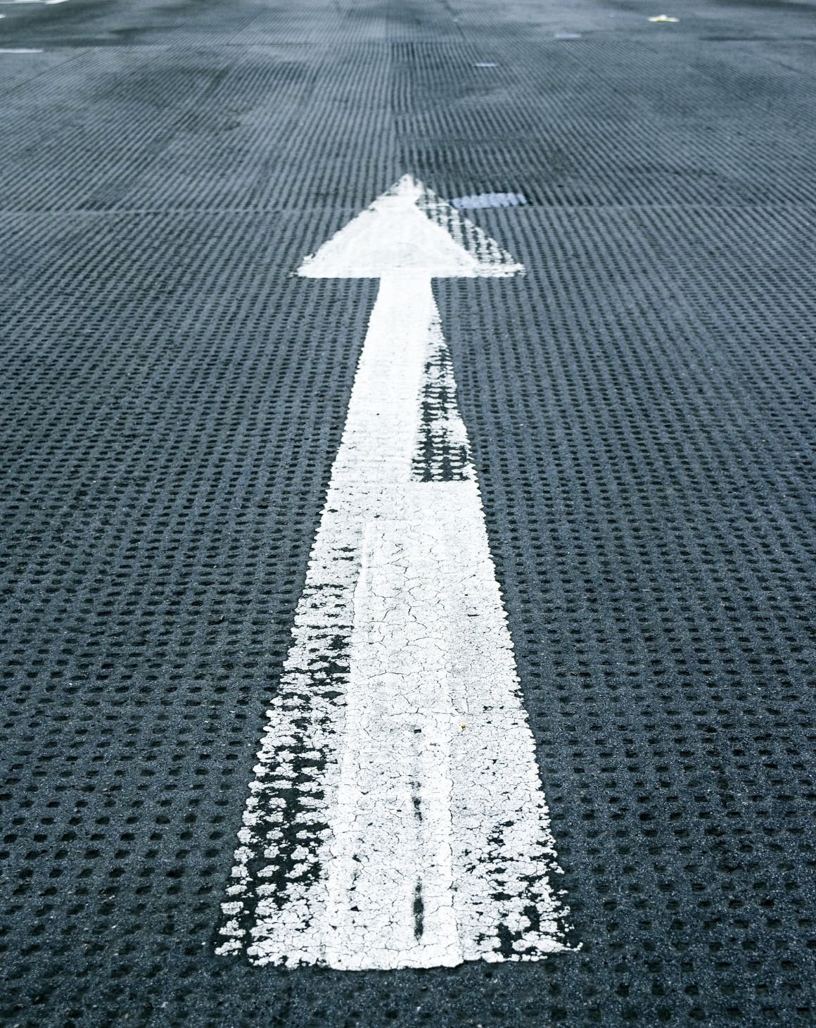 An arrow sign on the street ground