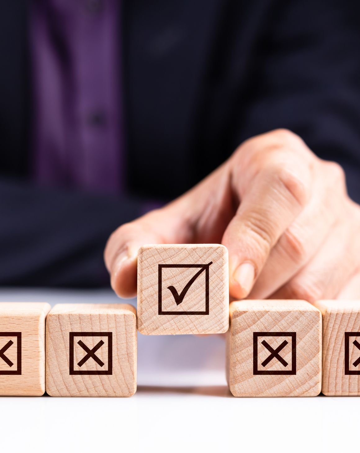 A person holding a wooden cube with checkmark sign