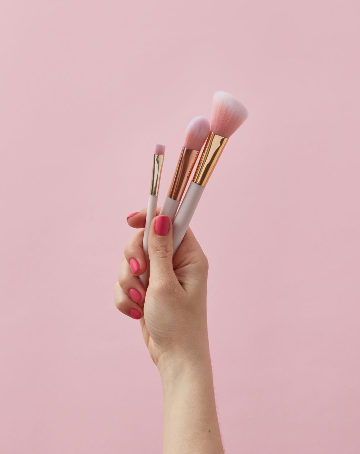 A female hand holding makeup brushes