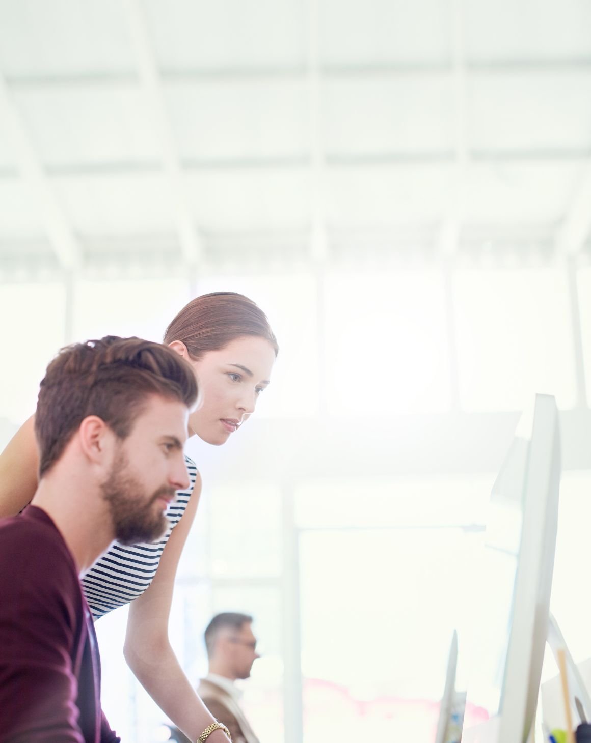 a man and a woman sitting in front of a computer in an office setting