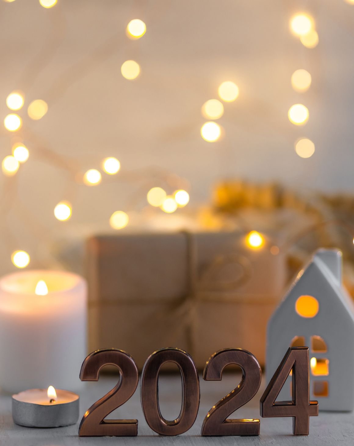 image with a wrapped gift, candles, string lights and a 2024 plaque