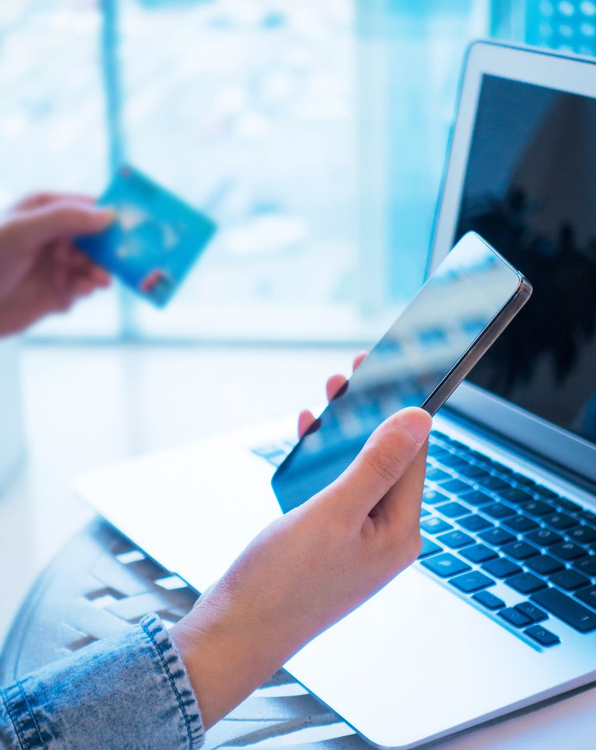 A woman holding a mobile phone and shopping online on a laptop