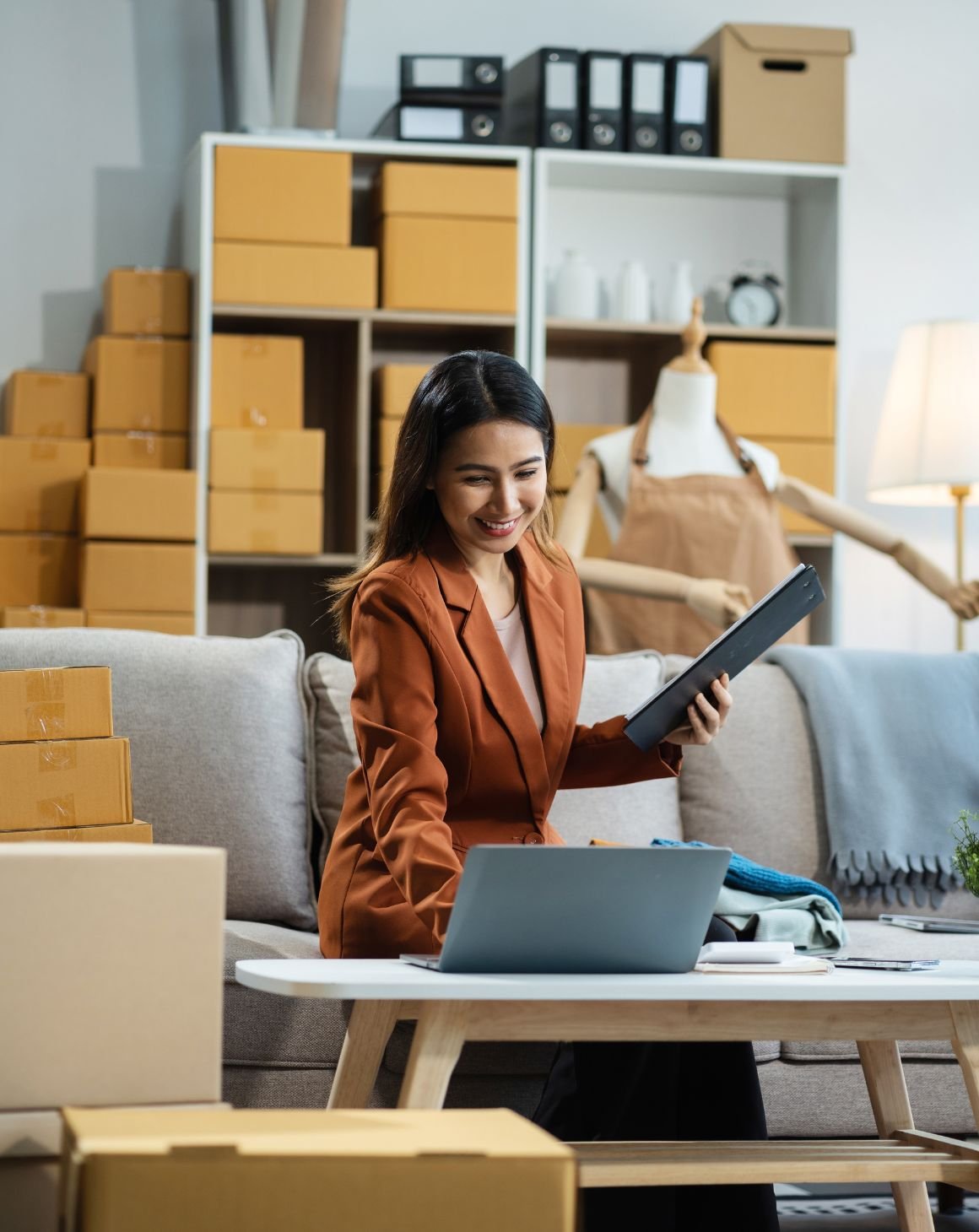 Woman sitting at a desk with clipboard and laptop