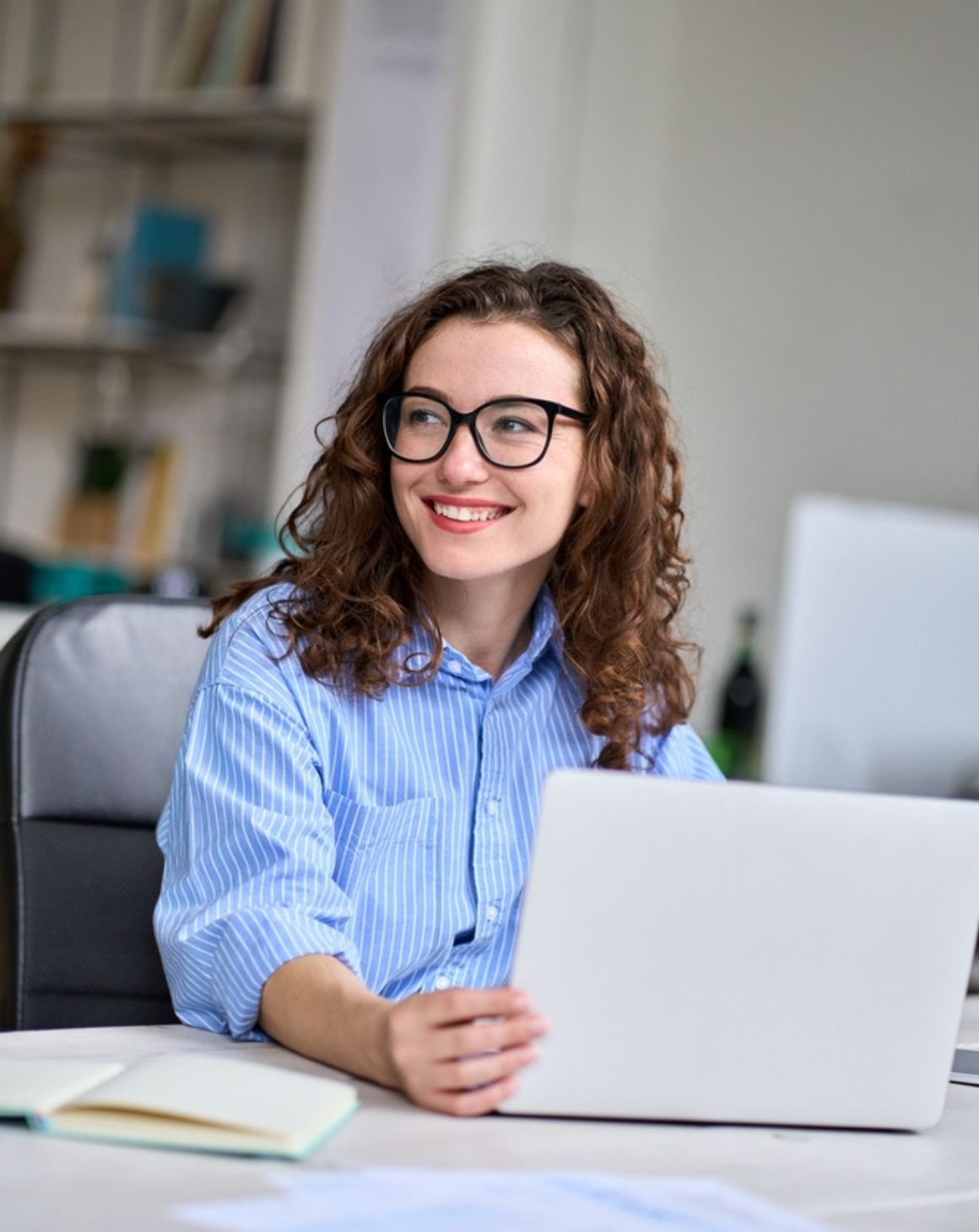 smiling woman sitting on a desk on a laptop