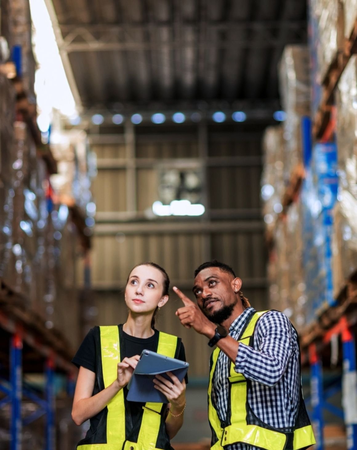 a man and a woman standing in a warehouse pointing