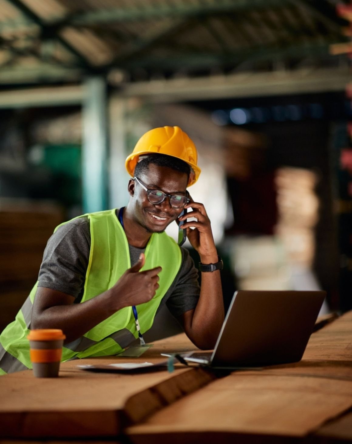 man in a hard hat and safety vest sits at product pallet